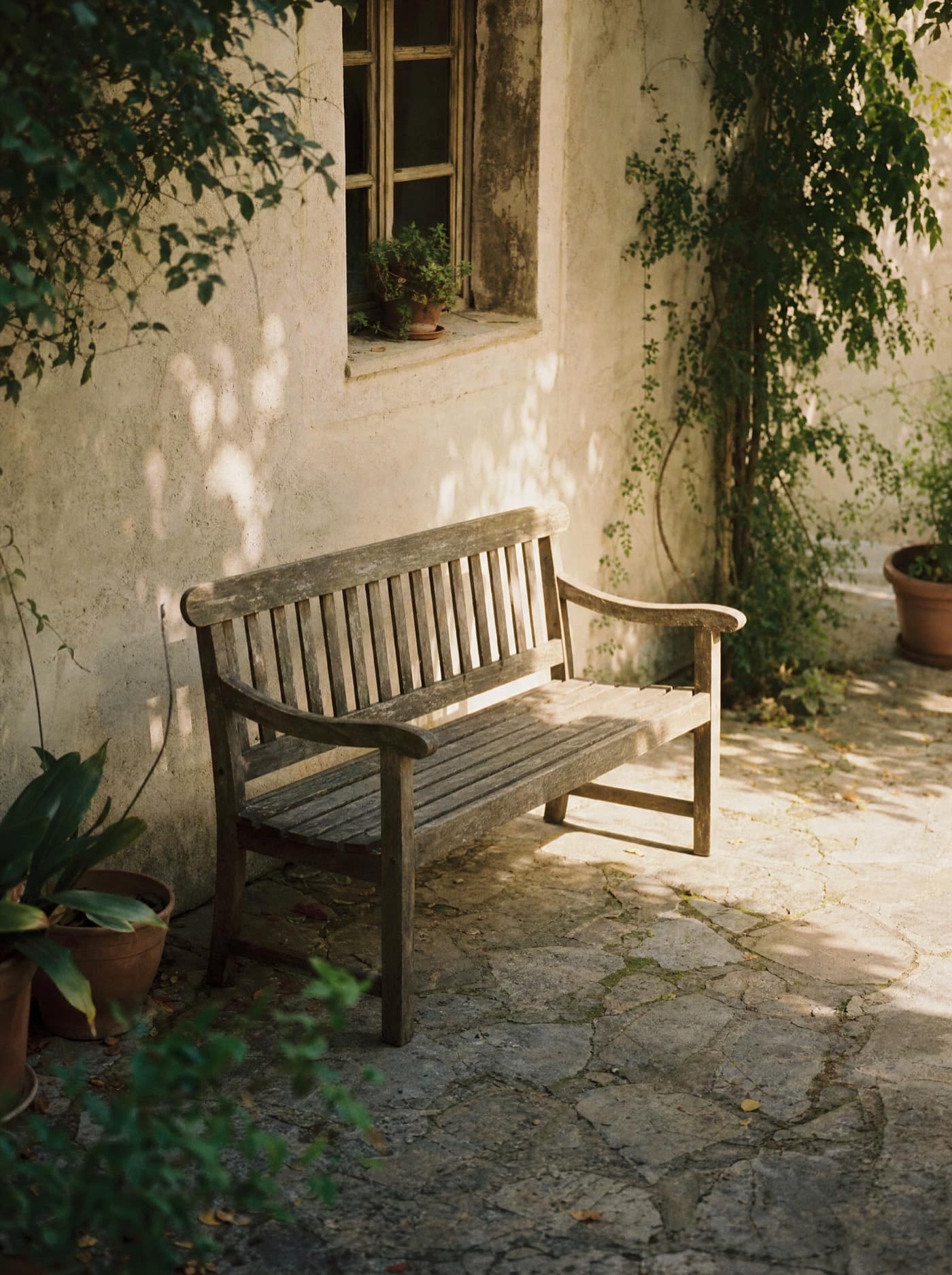 Ein leiser Innenhof mit einer einzelnen Bank im Schatten, frühes Licht. Keine Menschen im Bild — ein Moment zum Durchatmen, bevor das Praktische beginnt.